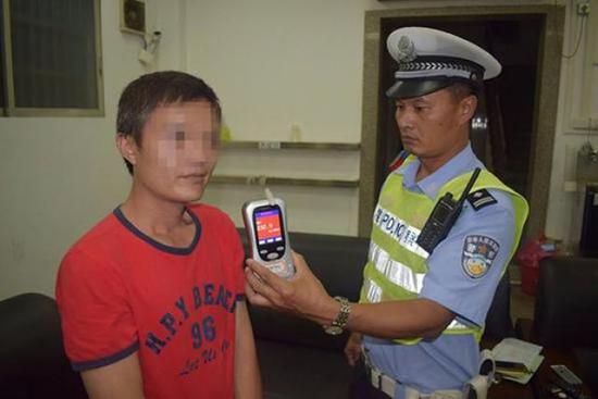 ↑谢某在接受吹气酒精检测。江门交警供图