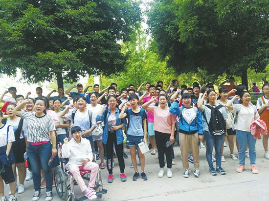 走进考场前,脑瘫女生李某和同学们一起为高考加油鼓劲。