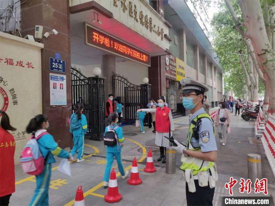 资料图:郑州市金水区文化路第二小学门前,交警指引小学生入校。郑州市交警一大队供图