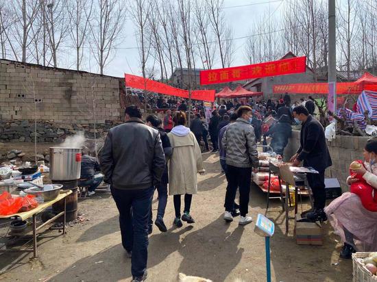 村里稍微平缓的坡地,杨树间挂上了红色的横幅,不少村民也就地做起了生意。
