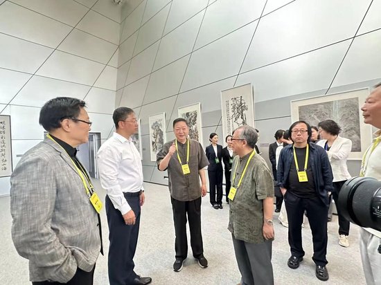 ▲ 佘玉奇向大连市领导介绍参展特邀画家代表