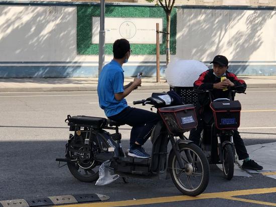 两位快递小哥在路边交流。新华社记者 王辰阳摄