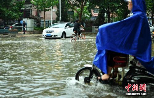 7月16日,河北石家庄一条马路积水严重,民众涉水骑行。当日,该省气象台发布暴雨蓝色预警,多地遭受暴雨袭击。中新社记者 翟羽佳 摄