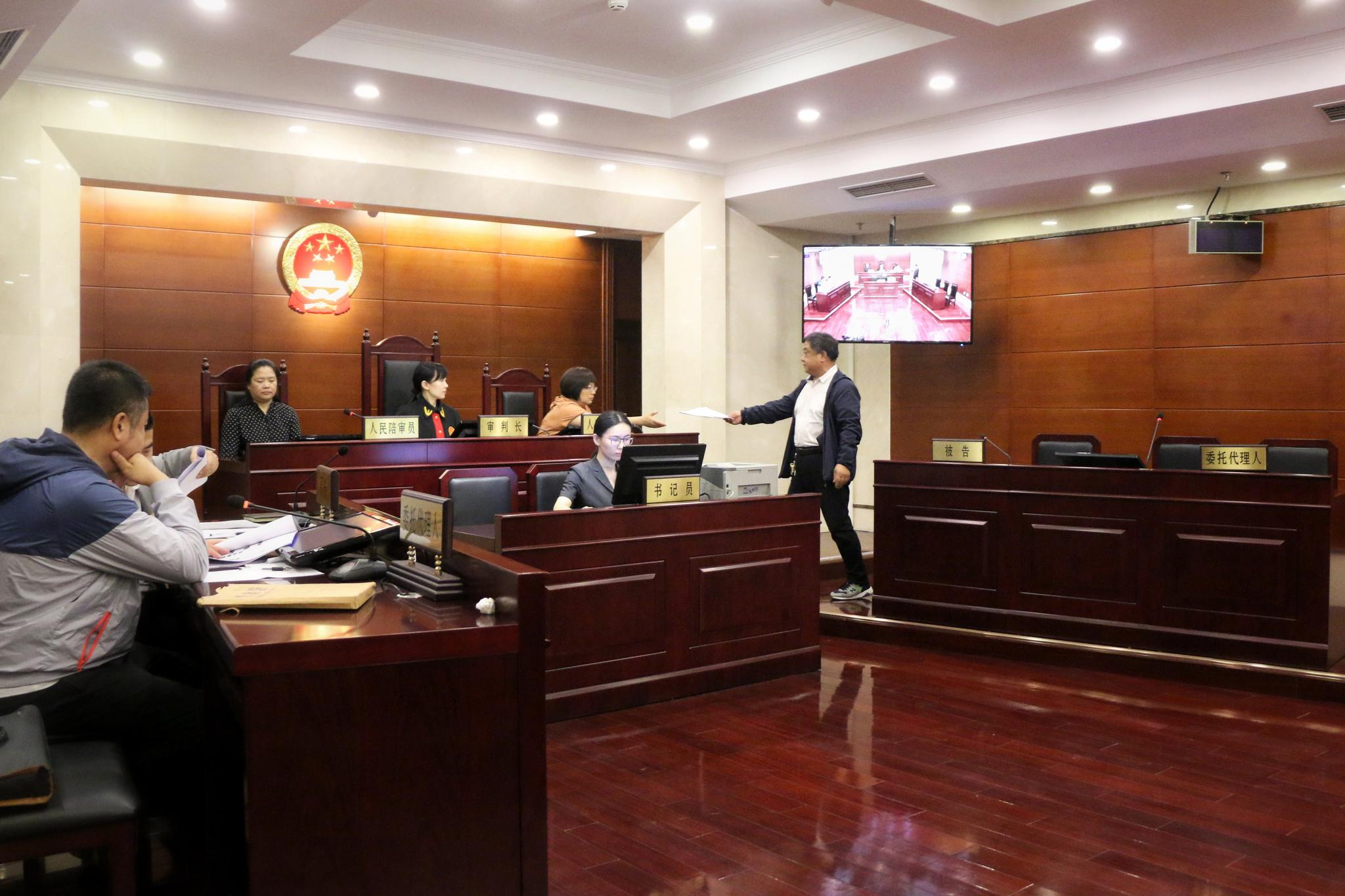 被告委托代理人庭上向审判长提交证据。实习生 陈婉婷 摄