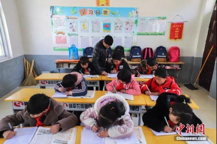 资料图:老师在教室里给小学生们辅导作业。