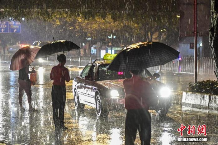 资料图：广州市民冒雨在路边等待出租车。 中新社记者 陈骥旻 摄