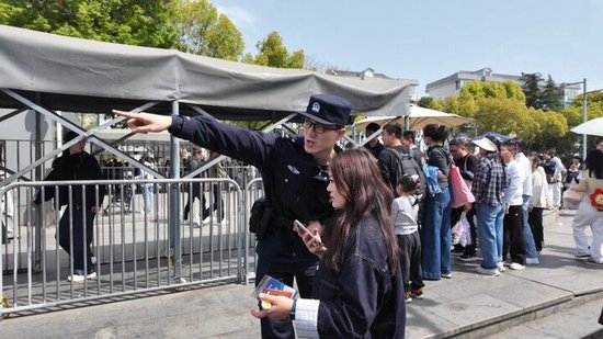  图释：民警引导外地游客参观缅怀 拍摄：张梵彬