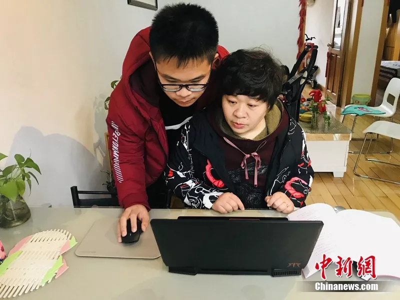 王晓丽母子一起看成长档案 张芹 摄