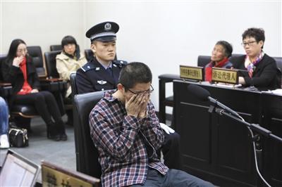 昨日,41岁的朱某受审时,听到律师辩护提及其家中上有老下有小时捂住了脸。1997年,朱某参与一起打架事件导致一人死亡,之后变换身份潜逃20年。 新京报记者 王嘉宁 摄