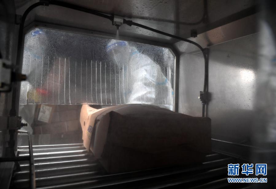 1月22日,在郑州市进口冷链食品集中监管仓(惠济仓),工作人员将进口冷链食品放入自动消毒机。