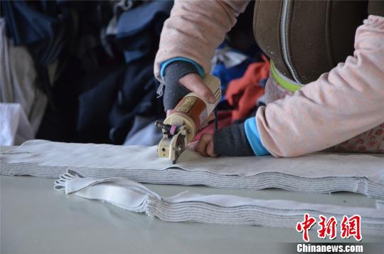 图为姚家坡村村民正在裁布、制作秋裤。 郝学娟 摄