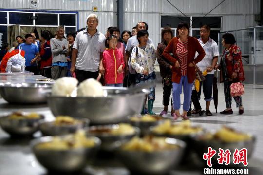 在山东寿光集中安置点,民众有序排队领取馒头、蔬菜等食物,一日三餐得到保障。 梁犇 摄