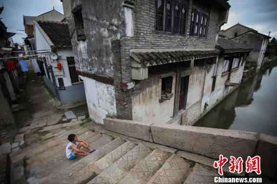 一名孩子坐在石拱桥上玩耍。 泱波 摄