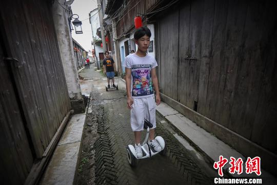 骑着平衡车的少年从老街上穿过。 泱波 摄