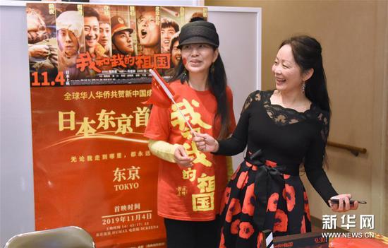 11月4日，在日本东京，观众在首映式上与海报合影。新华社记者 冮冶 摄