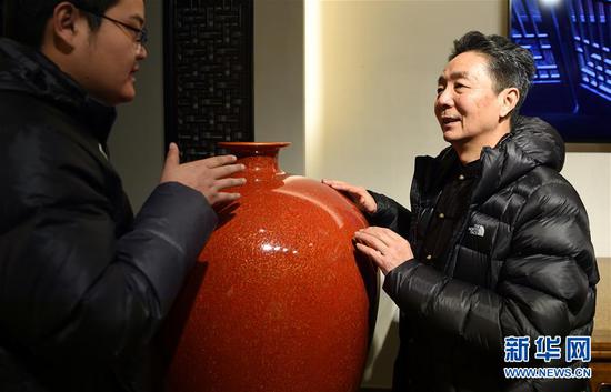 1月8日,在安徽省黄山市的而可漆艺工作室,国家级徽州漆器髹饰技艺传承人甘而可(右)向参观者介绍自己制作的漆器。