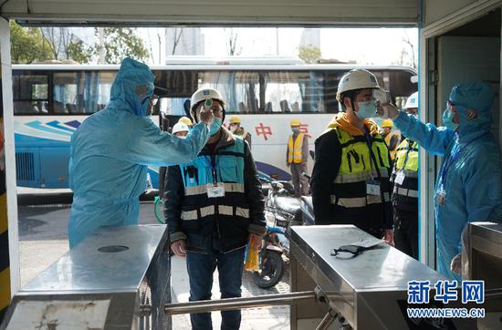 3月14日,在南京葛洲坝长江尊邸项目工地门前,员工在进入施工现场前接受体温测量。新华社记者 季春鹏 摄