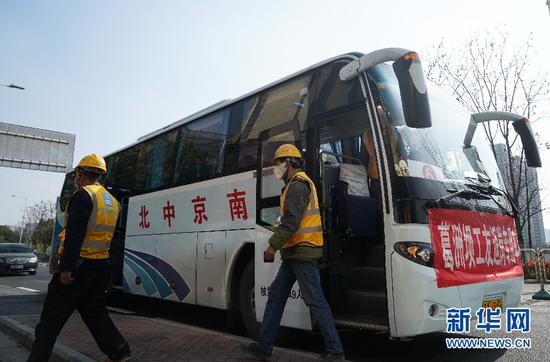 3月14日,在南京葛洲坝长江尊邸项目工地门前,工人从接送专车走下,准备进入施工现场。新华社记者 季春鹏 摄