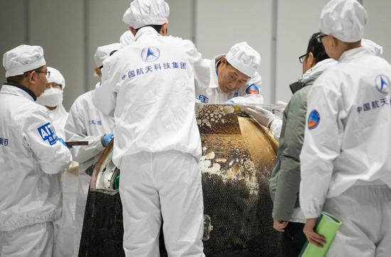 2020年12月17日,在中国航天科技集团五院,科研人员打开嫦娥五号返回器舱门,取出装有月球样品的容器并进行称重。新华社记者 金立旺 摄