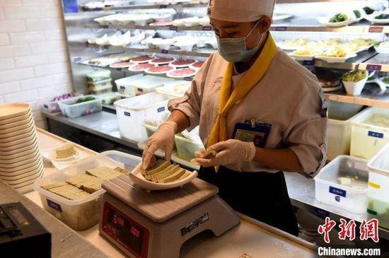 资料图:服务员正在称重摆盘半份菜。 周毅 摄
