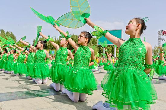 2019年5月31日,甘肃张掖滨河新区水天一色广场上,老师和学生们共同表演大型文艺节目,庆祝六一国际儿童节。