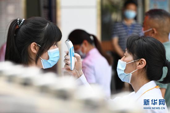 6月7日,在安徽省合肥市第九中学考点,考生(左)步入考场前接受测温。新华社记者 张端 摄