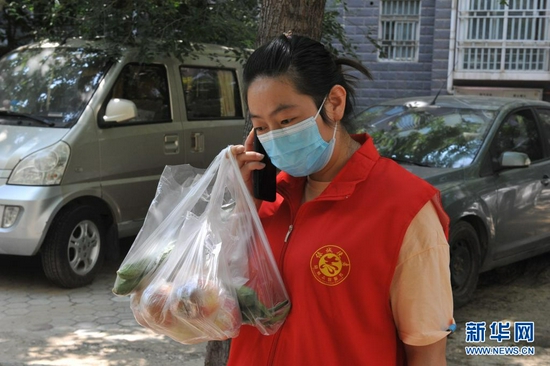 8月3日,在郑州市二七区长江路街道办事处长江路社区江山书香名邸小区,便民超市老板魏晓迪联系电话下单的居民接收购买的物品。新华社记者 韩朝阳 摄