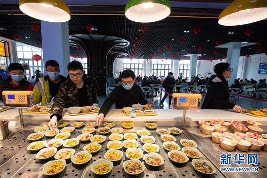 2月11日,在四川大学望江校区东二食堂,就餐的同学们排队取餐。