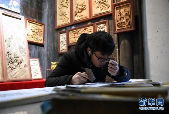 1月8日，在安徽省黄山市徽州区呈坎村，一名年轻人在制作木雕作品。