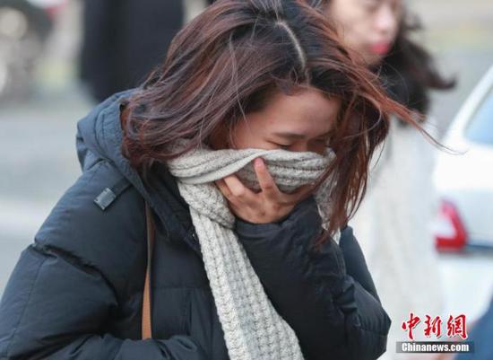 一名女性寒风中出行。