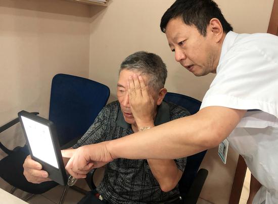 常州激光医院副院长、眼科主任张雷，为做了屈光性白内障手术的蒋先生检测视力。