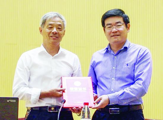 学校党委副书记倪永宏为顾秋亮(左)颁发校外辅导员聘书