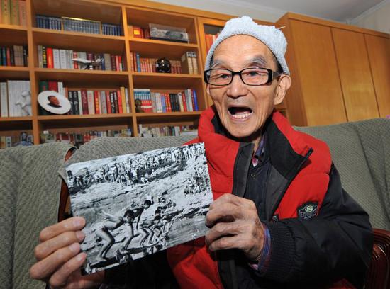 2008年4月3日,徐肖冰老人向记者介绍他1943年在延安清凉山下拍摄的游泳比赛的照片。新华社记者何俊昌摄