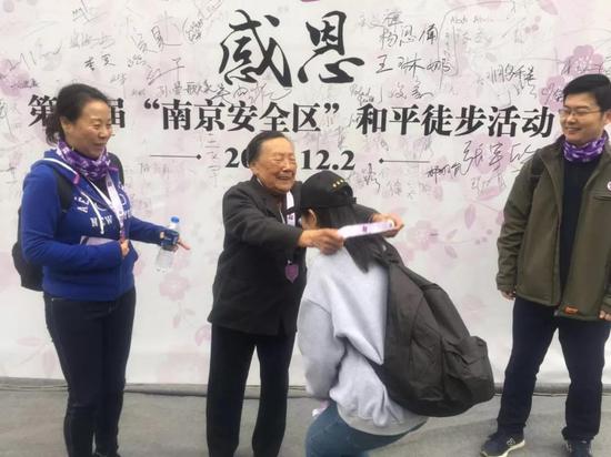 南京大屠杀幸存者夏淑琴为徒步参与者颁发了和平奖章