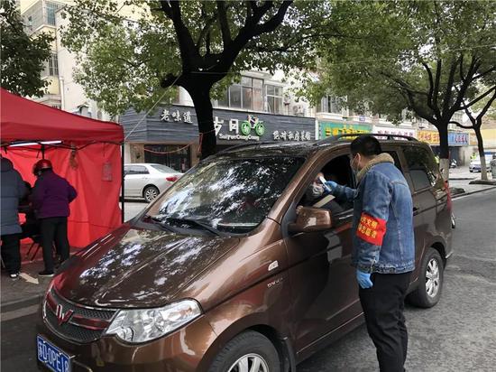志愿者对已经办理车辆通行证人员进行体温测量