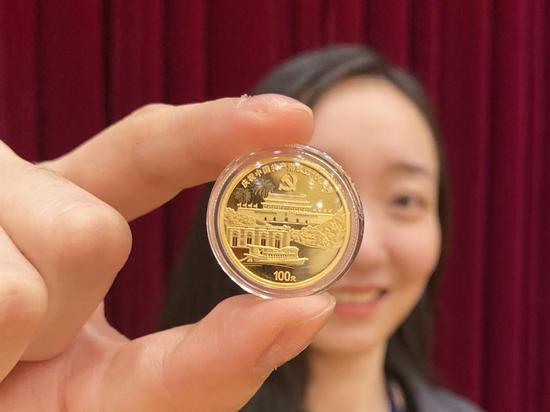 (一名金币总公司员工向记者展示一枚8克金质纪念币。新华社记者吴雨 摄)