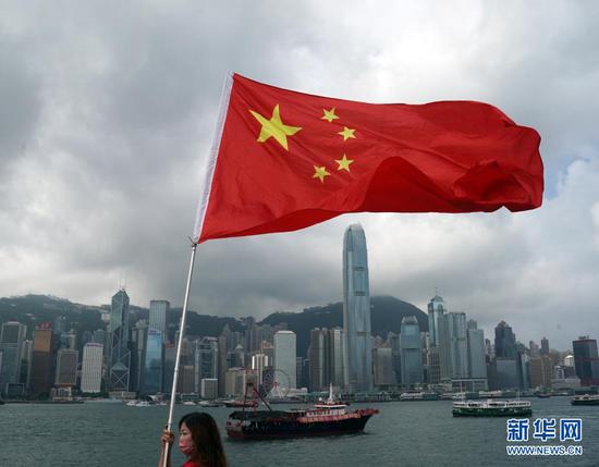 7月1日,在香港尖沙咀,香港市民挥舞国旗庆祝。新华社记者 李钢 摄