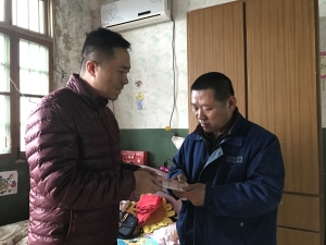 现代快报记者将陈祝老人的5000元爱心捐款送到快递小哥父亲(右)手中 朱臻 摄