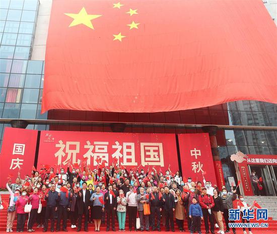 在北京市朝阳区文化馆举办的国庆专题活动上,嘉宾与国旗合影(10月1日摄)。 新华社记者 金良快 摄