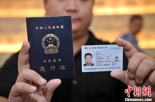 资料图:市民展示电子往来港澳通行证(右一)和纸质港澳通行证(右二)。中新社发 陈超 摄