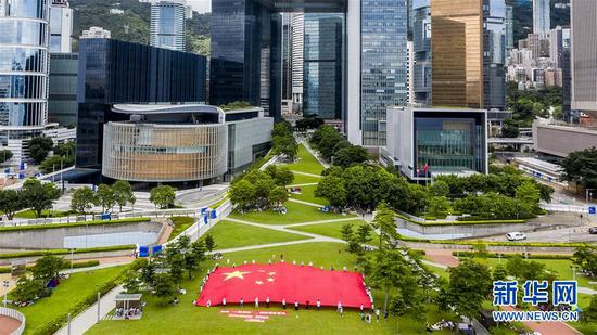 6月25日，市民在香港添马公园展示巨幅国旗（无人机照片）。新华社发