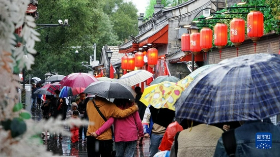 10月6日,游人冒雨游览北京南锣鼓巷。新华社记者 李欣 摄