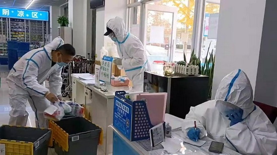 11月6日,三名工作人员在庄河市一家药房为封闭管控的居民提供药品配送服务。新华社记者蔡拥军摄