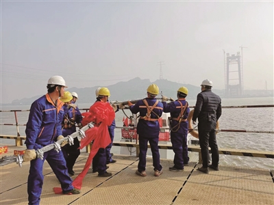 工人们为先导索系上红绳准备过江。 南京晨报/爱南京记者 陈彦 摄