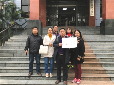 昨日,该案宣判后,几名被拐幼儿的家长拿着判决书在法院门口合影。受访者供图