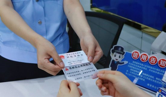六合公安分局民警将印有反诈口诀的身份证卡套送给办事群众。