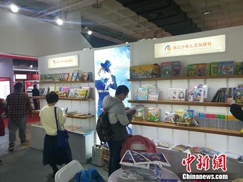 在展位前翻看童书的读者。上官云 摄