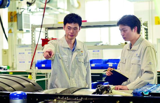 刘会神(左)与同事研究解放汽车设计工作。资料图片