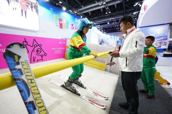一位小学生在吉林市展示区体验滑旱地滑雪设备。新华社记者鞠焕宗摄