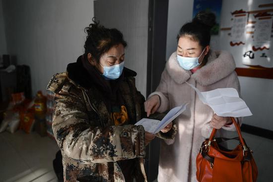 赵淑华(左)查看一位社区居民的核酸检测报告等相关防疫文件(2月15日摄)。新华社记者 许畅 摄